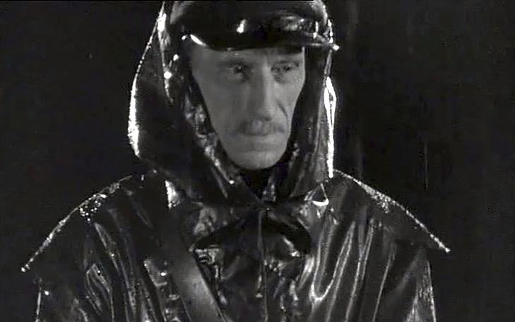 Кадр из фильма «Гибель сенсации», мужчина с усами в фуражке и целлофановом плаще