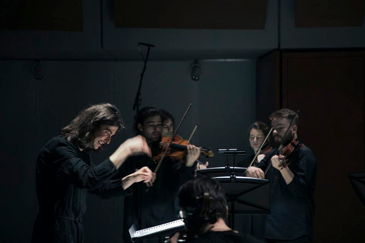 Титульное изображение для страницы события: фотография дирижера и группы музыкантов, играющих на скрипках