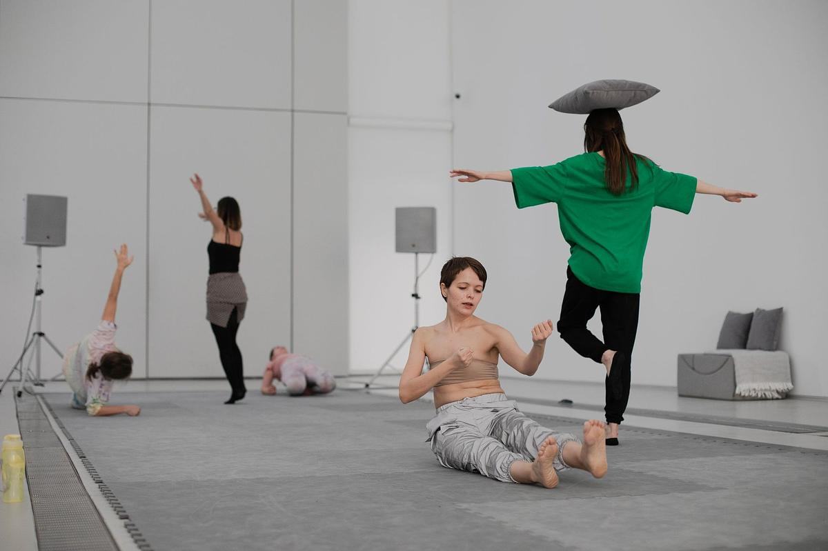 Титульное изображение для страницы события: люди в танц-классе на занятии, женщина балансирует на одной ноге с подушкой на голове