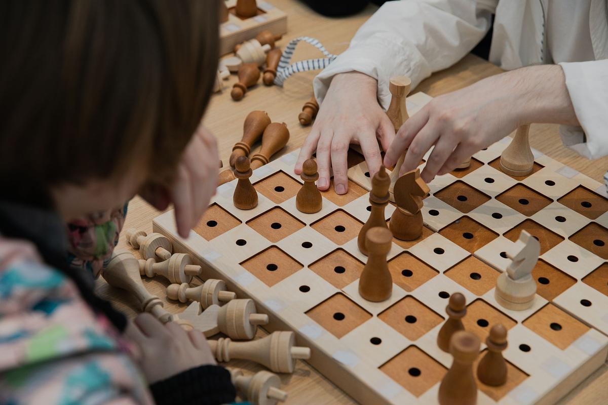 Два человека играют в шахматы на доске с дырочками