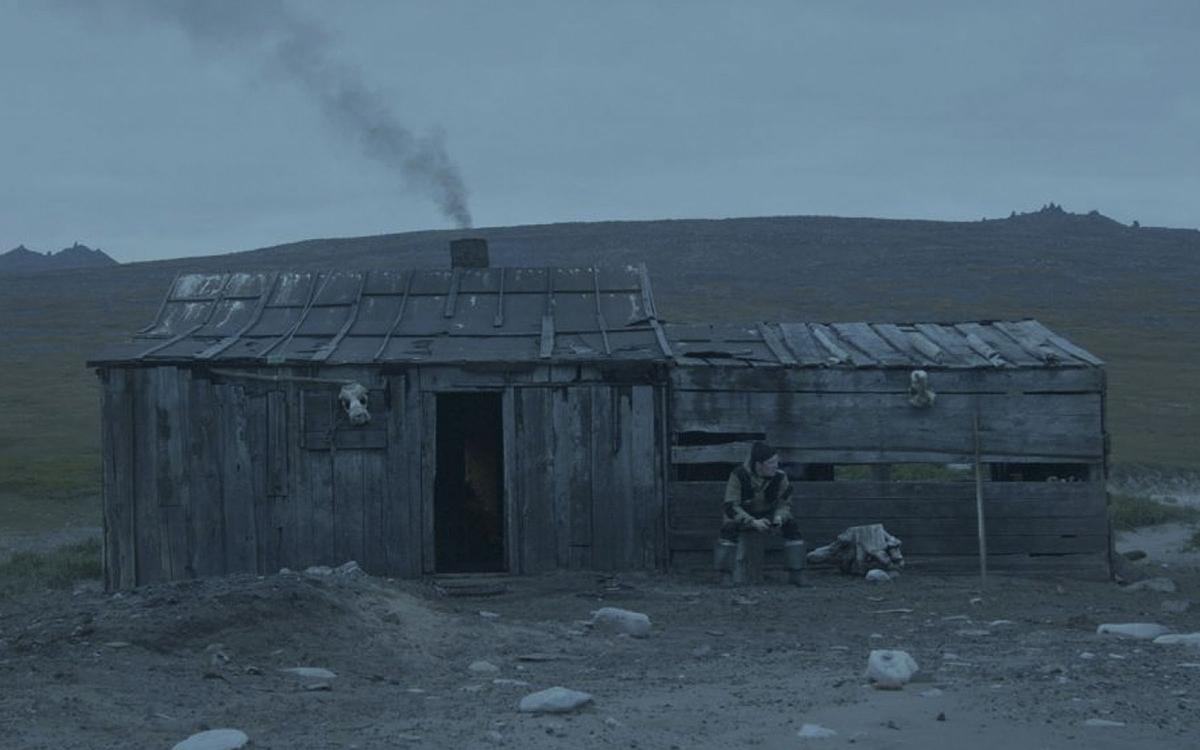 Титульное изображение для страницы события: кадр из фильма «Выход», человек сидит перед сараем посреди равнины