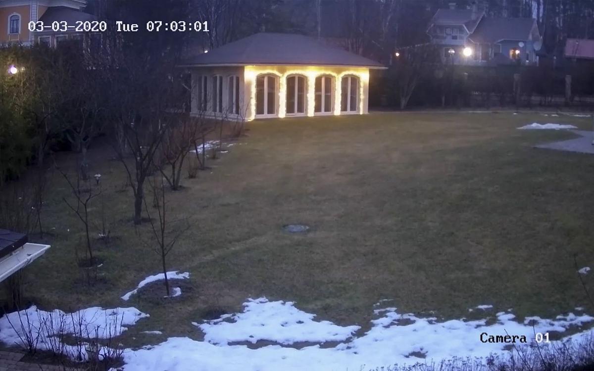 Титульное изображение для страницы события: кадр из фильма «Глаза Отара», кадр с записи камеры видеонаблюдения, зеленая лужайка в снегу и дом с подсвеченными окнами