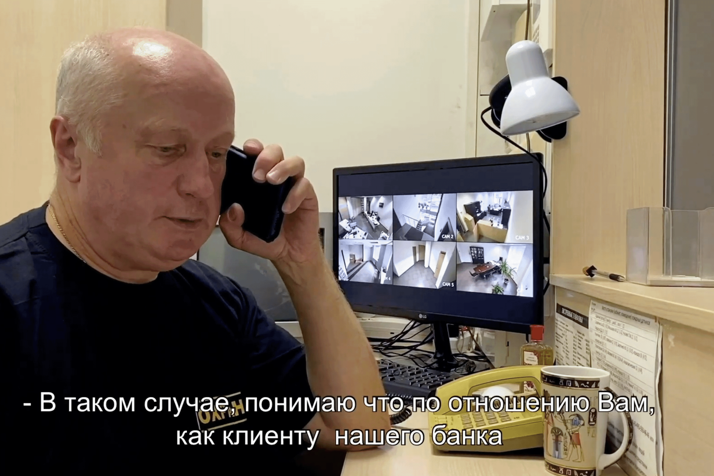 Анимация, мужчина среднего возраста с телефоном у монитора, посреди комнаты с телефоном и смотрит в камеру с биркой на груди с номером 2