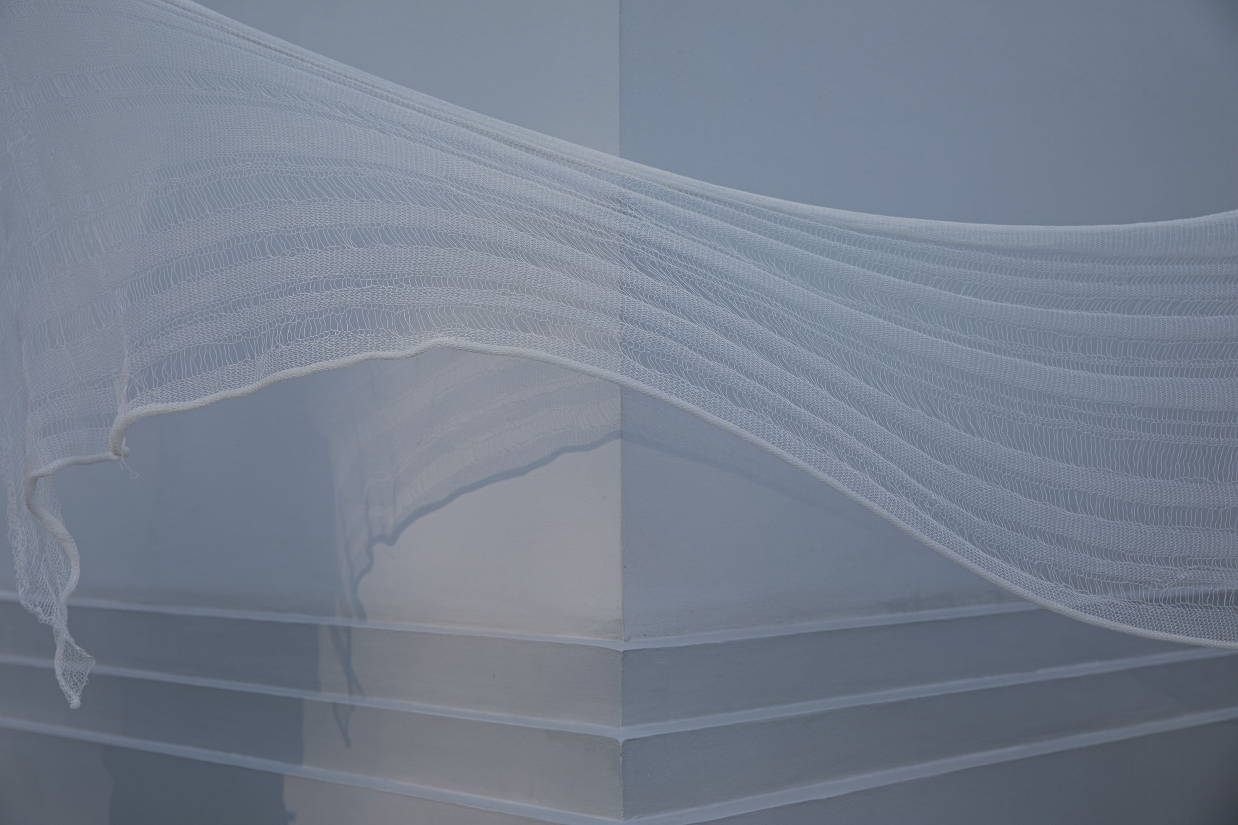 Фотография прозрачной ткани на фоне белого угла