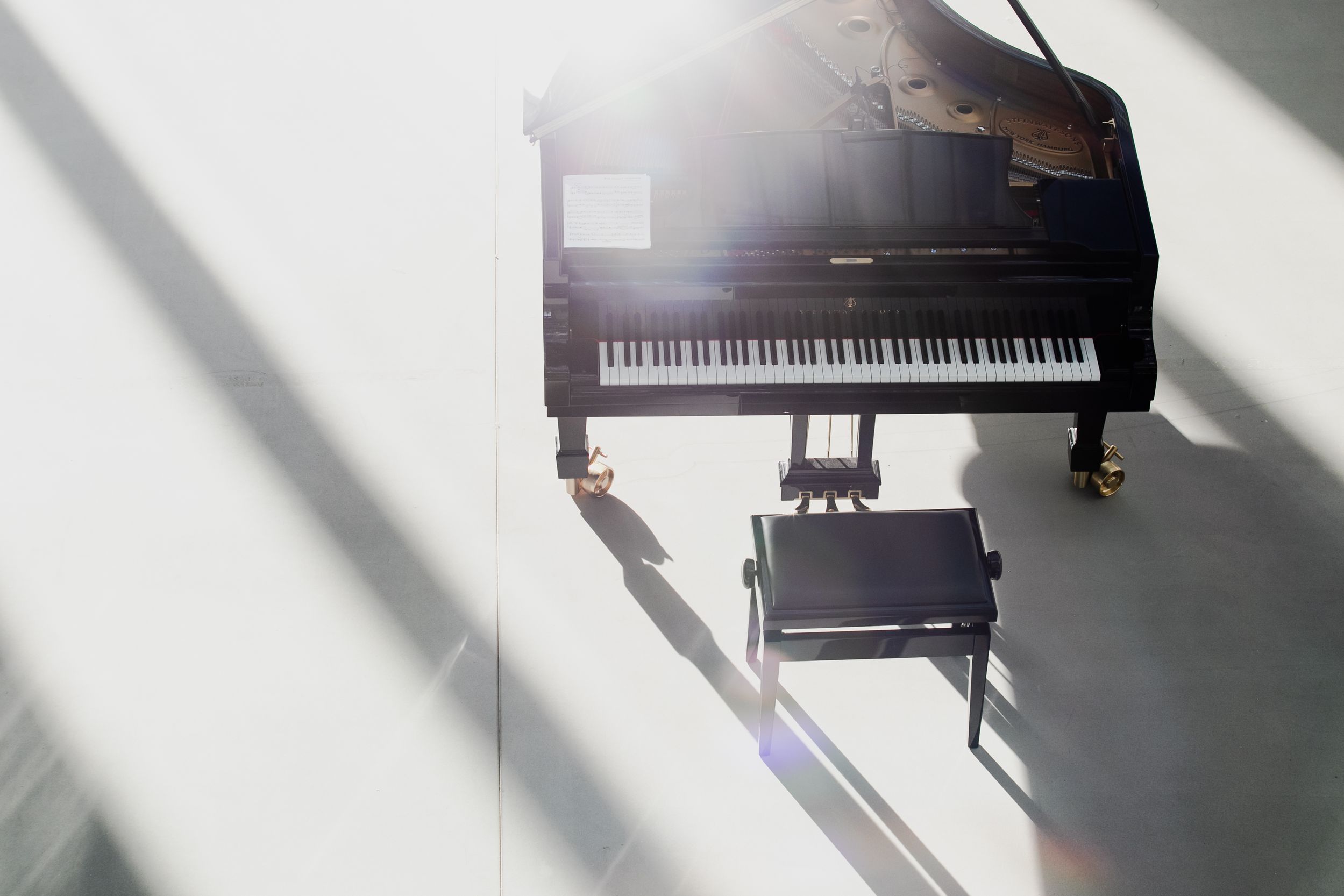Вид сверху на рояль, часть кадра засвечена солнцем