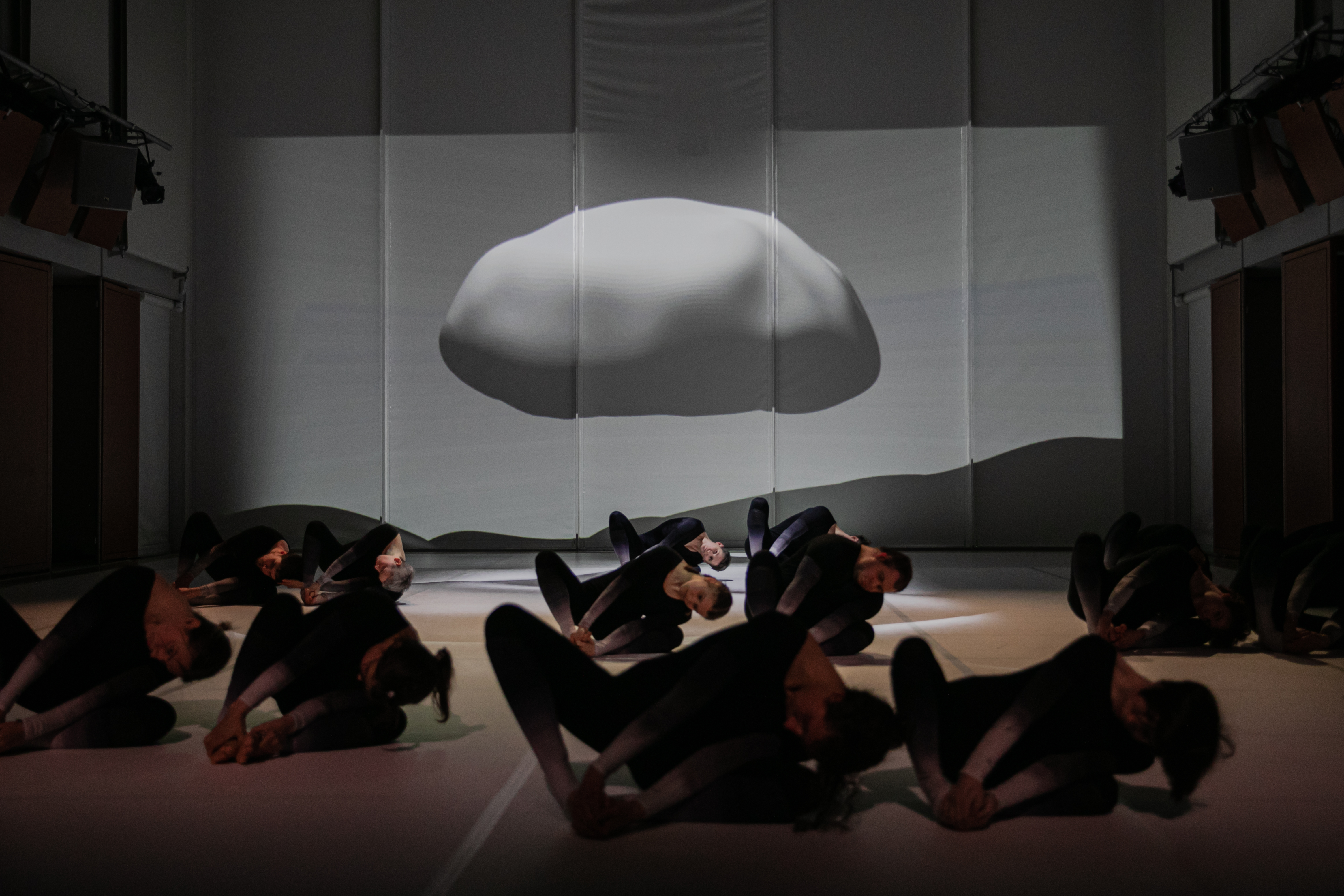 Люди кувыркаются по полу сцены, на фоне проекция 3-d модели камня