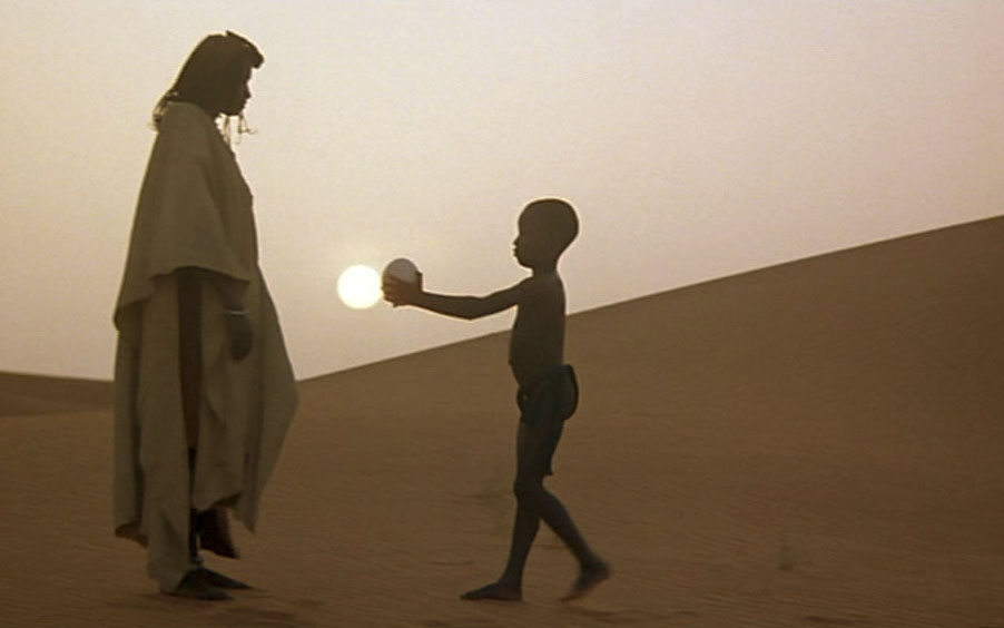 Мальчик протягивает шар женщине в пустыне
