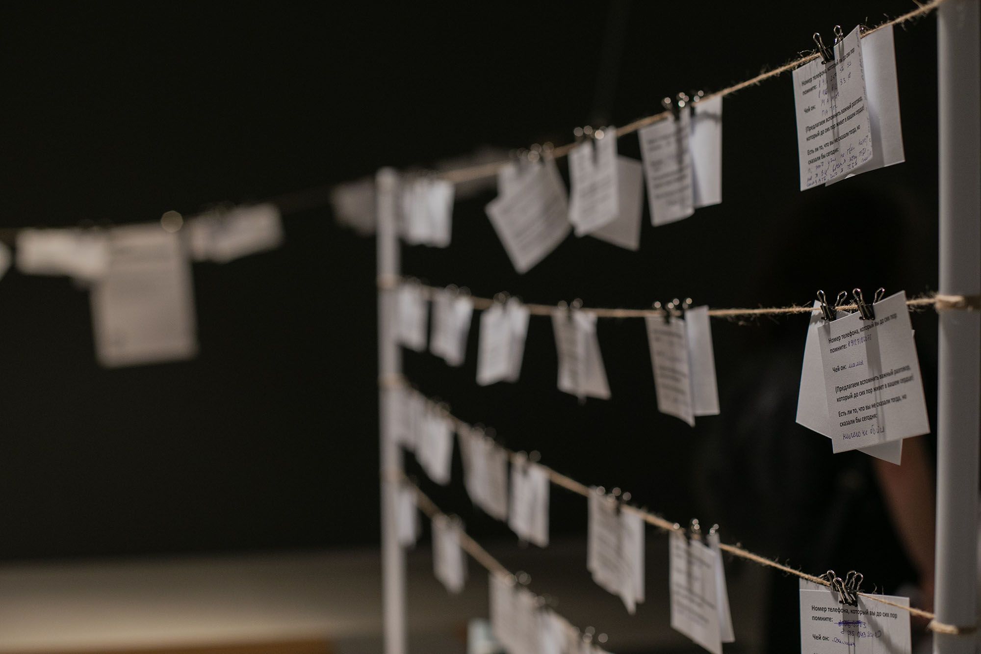 Фотография спектакля «Кладовая памяти», записки прицеплены к растянутым веревкам прищепками
